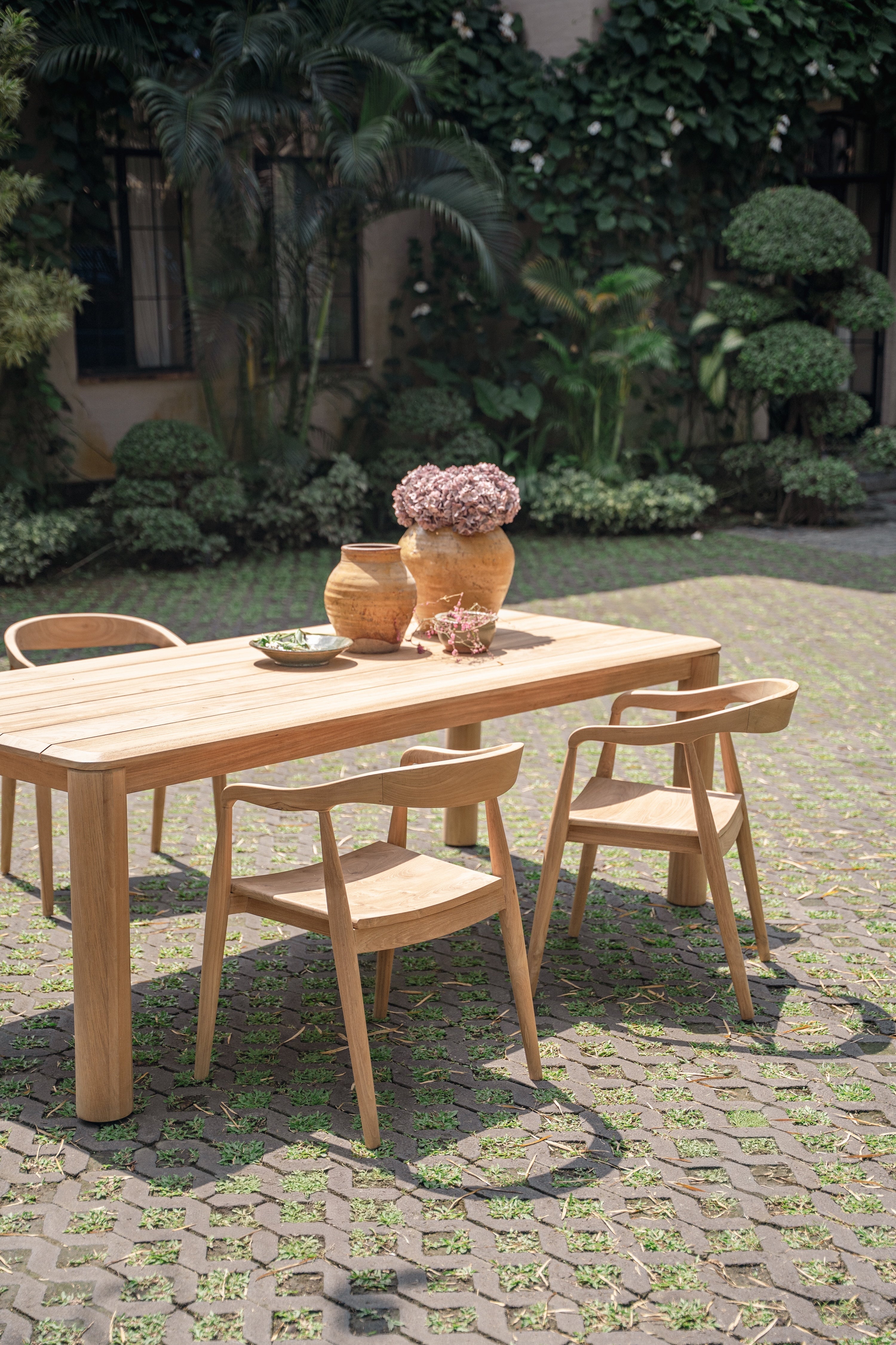 beautiful teak table and chairs set up in a green garden