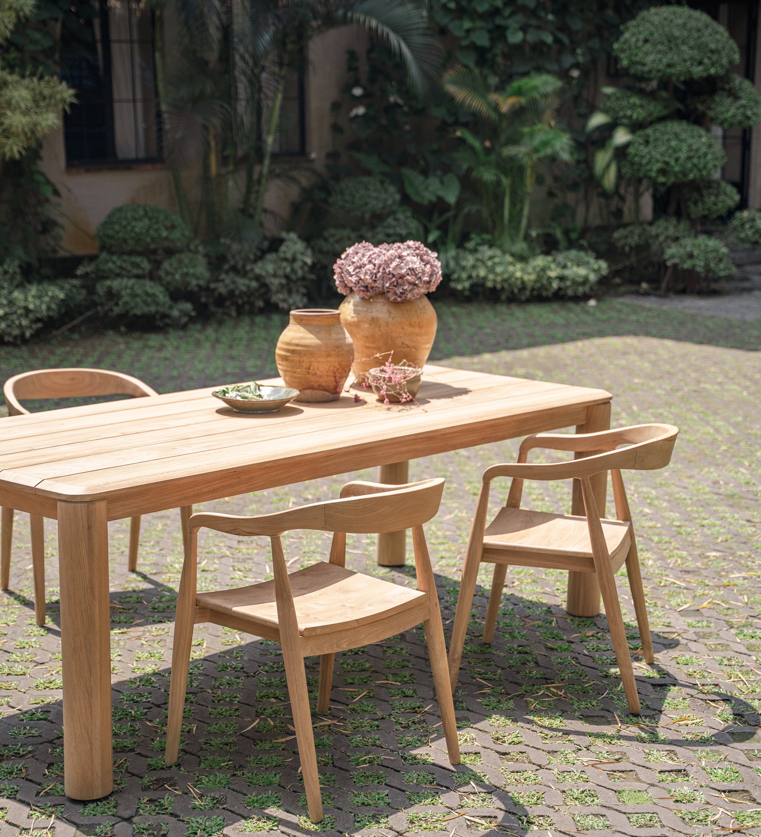 beautiful teak table and chairs set up in a green garden 