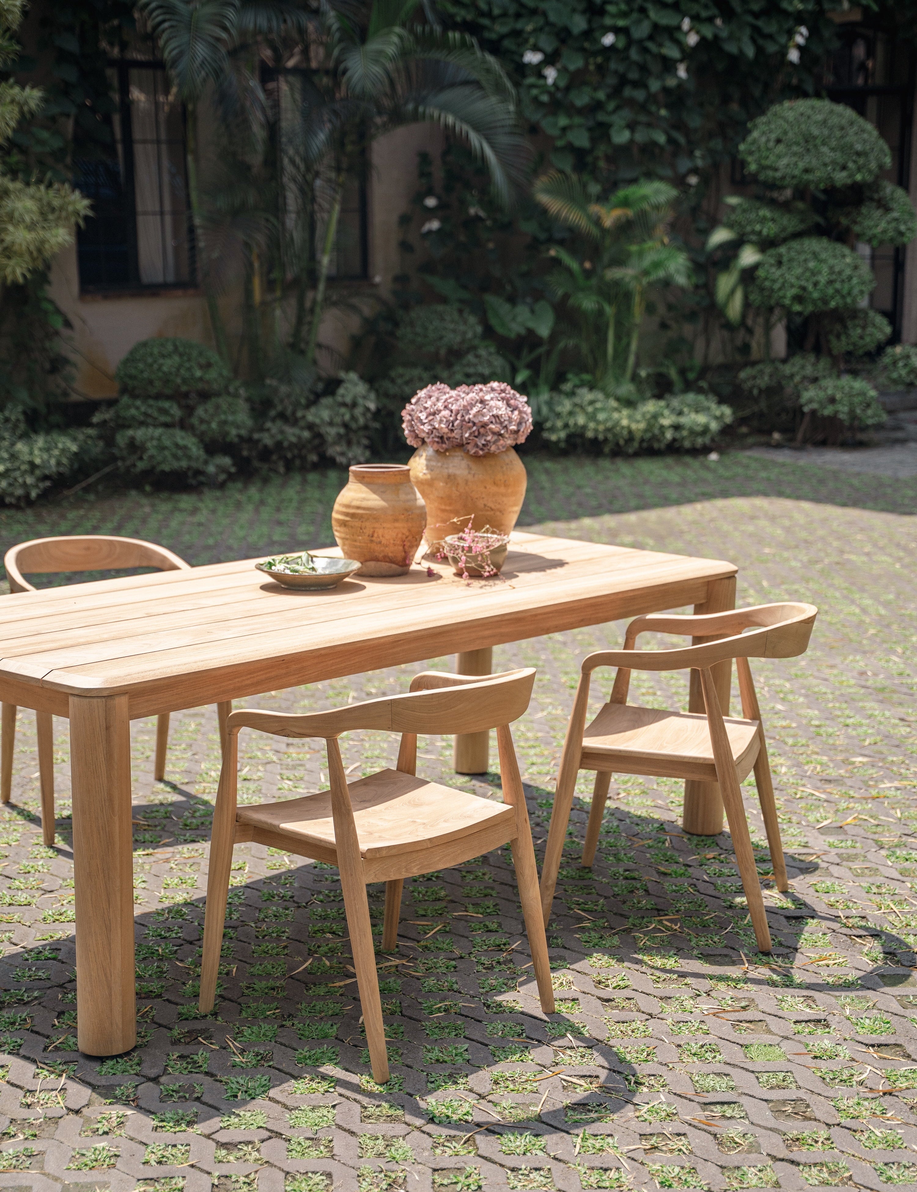 beautiful teak table and chairs set up in a green garden 