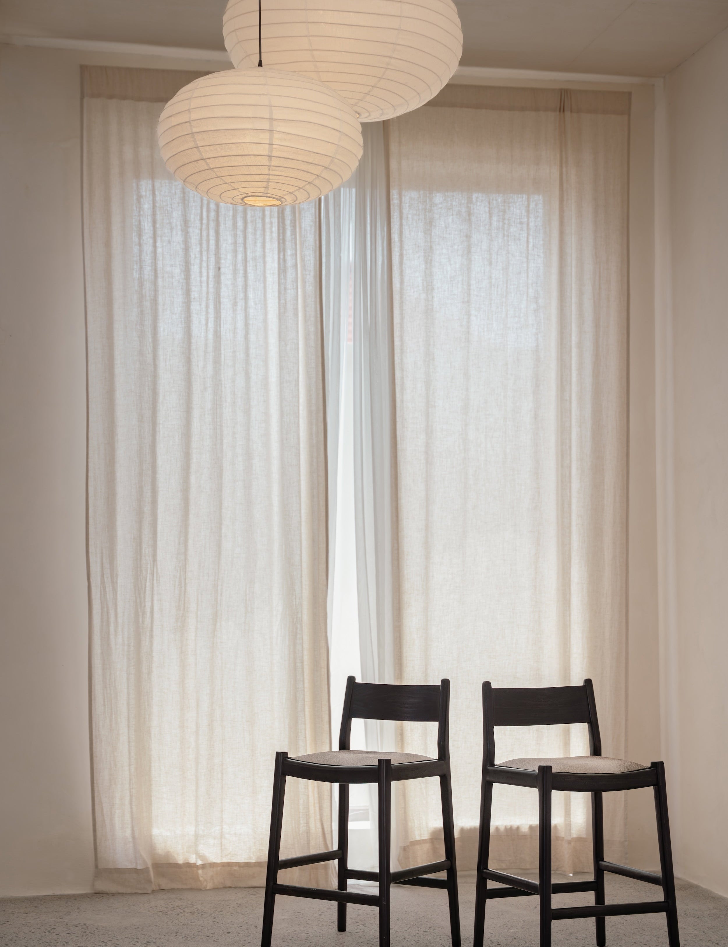 two dark teak and cowhide stools in a light filled room