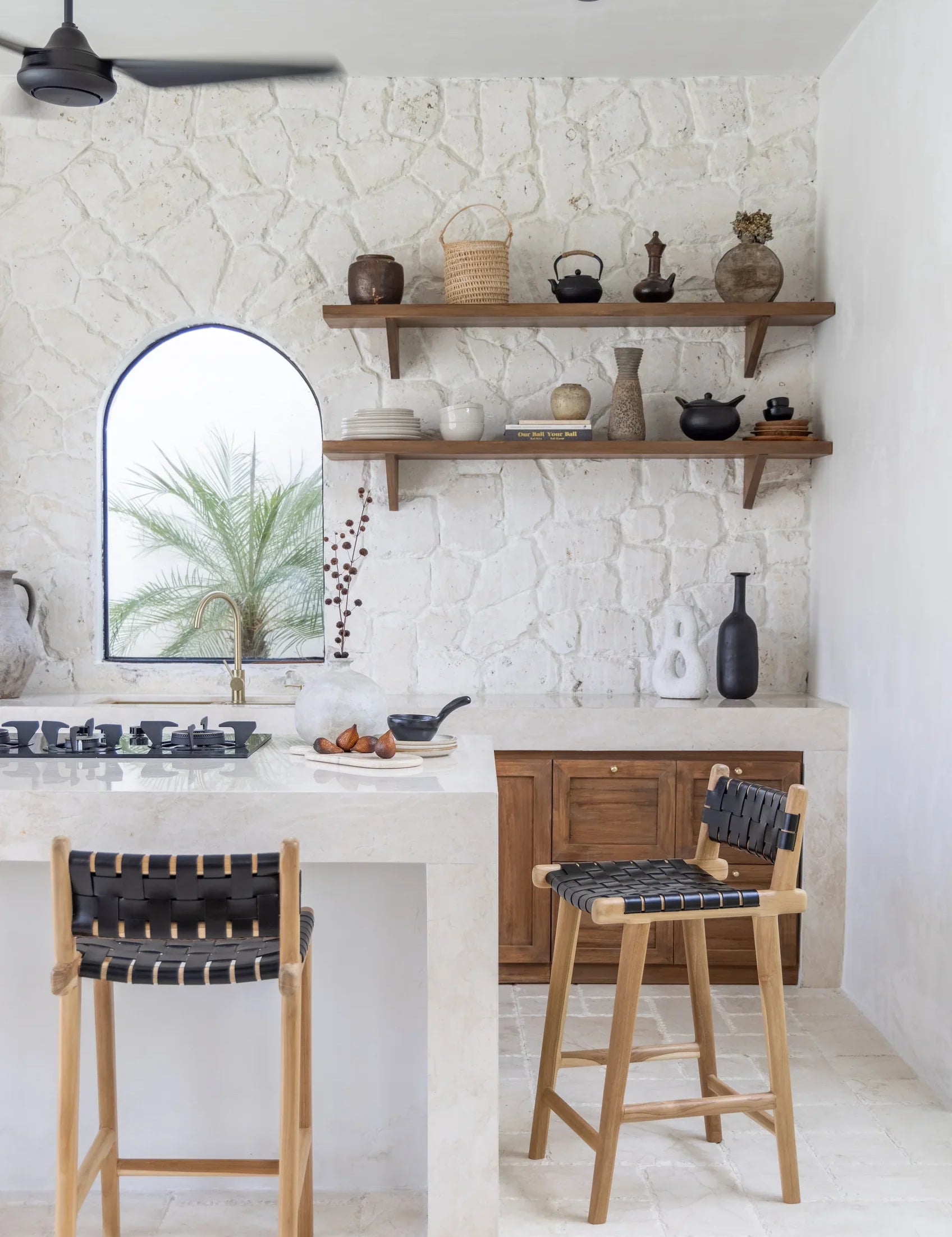 black leather and teak stool in a kitchen with floating wooden shelves