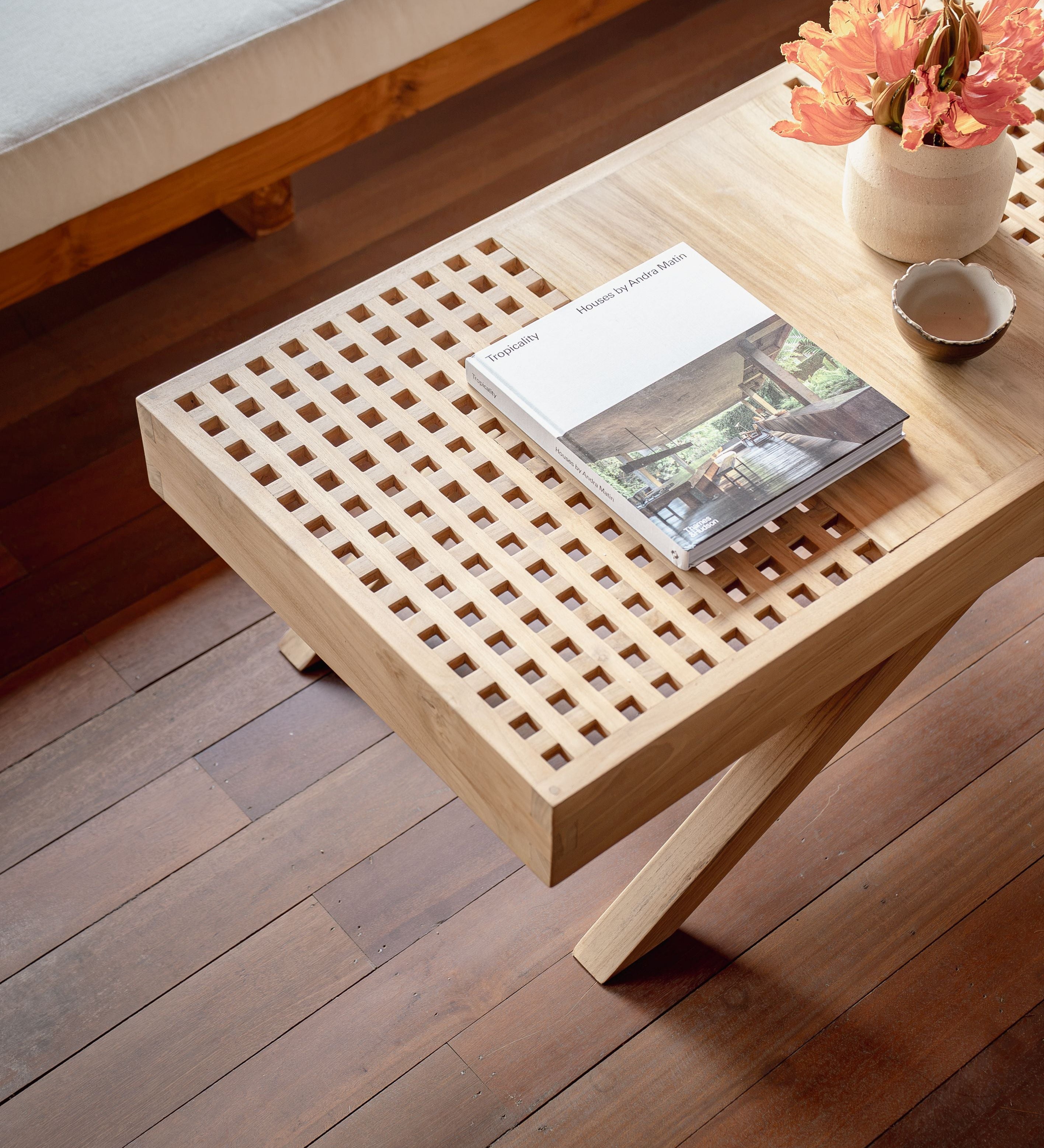 teak coffee table with flower and book on top as decoration