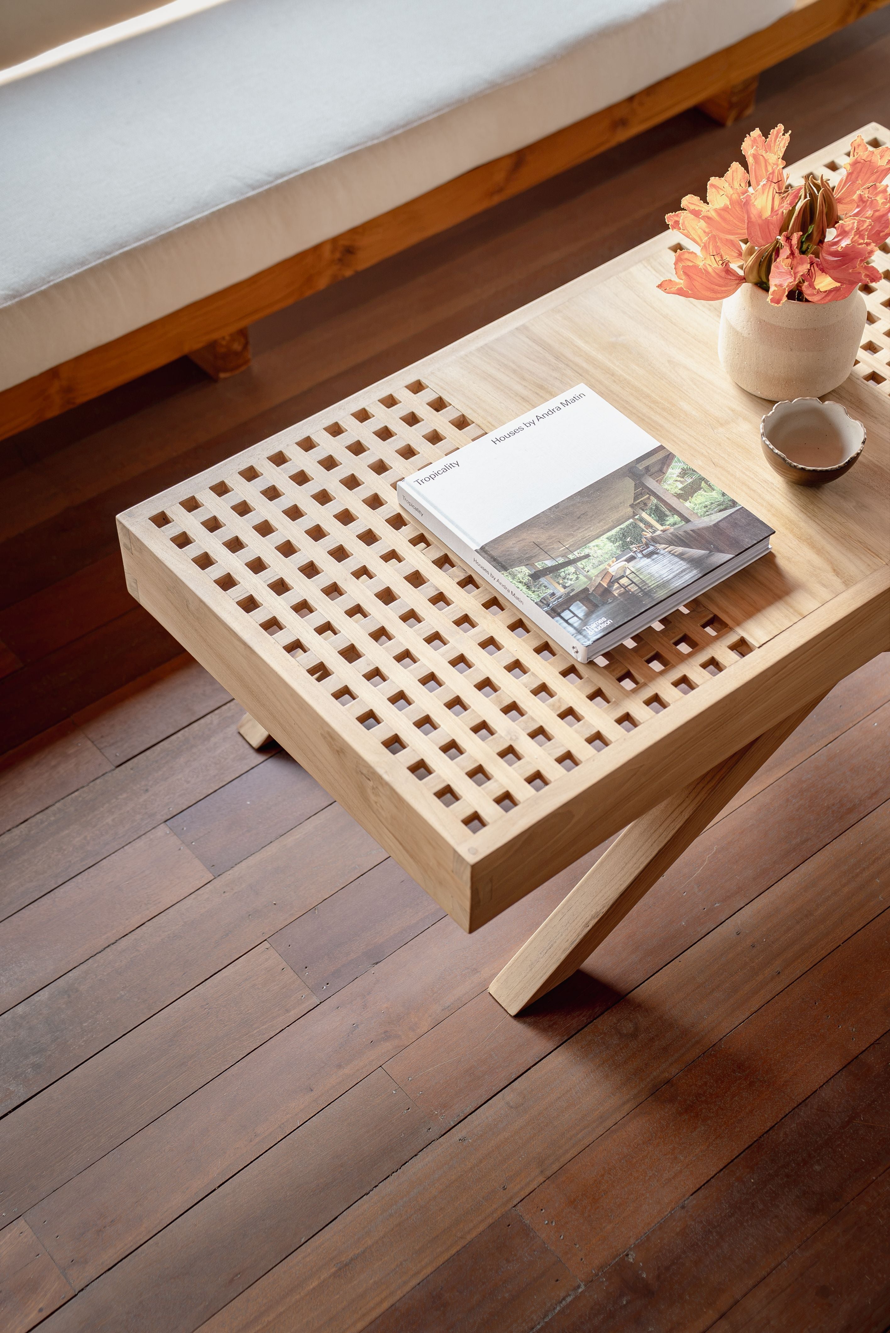 teak coffee table with flower and book on top as decoration