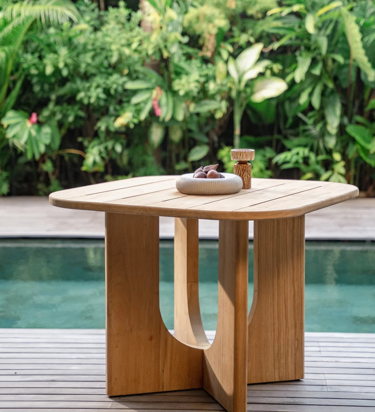 outdoor natural teak dining table by a pool in balinese villa