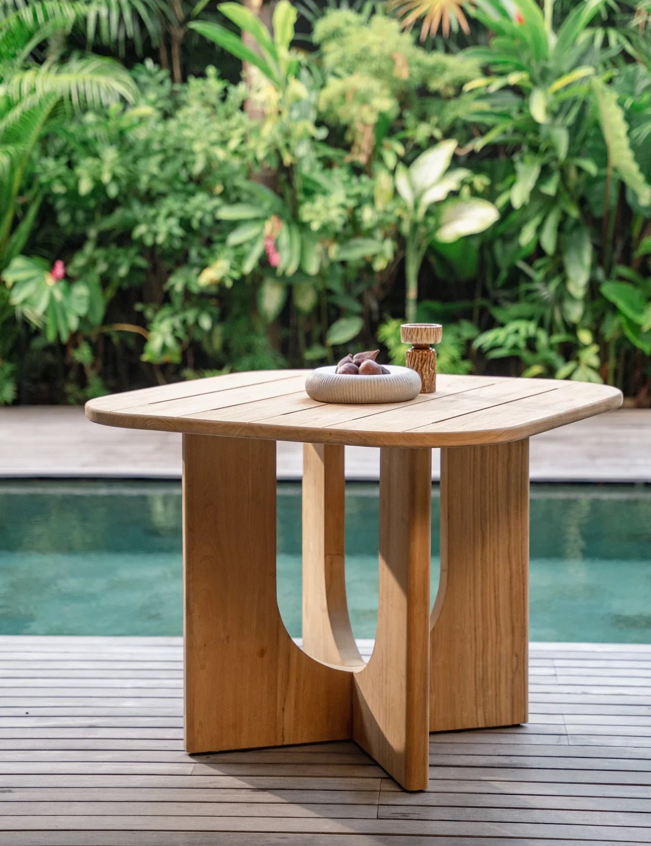 outdoor natural teak dining table by a pool in balinese villa