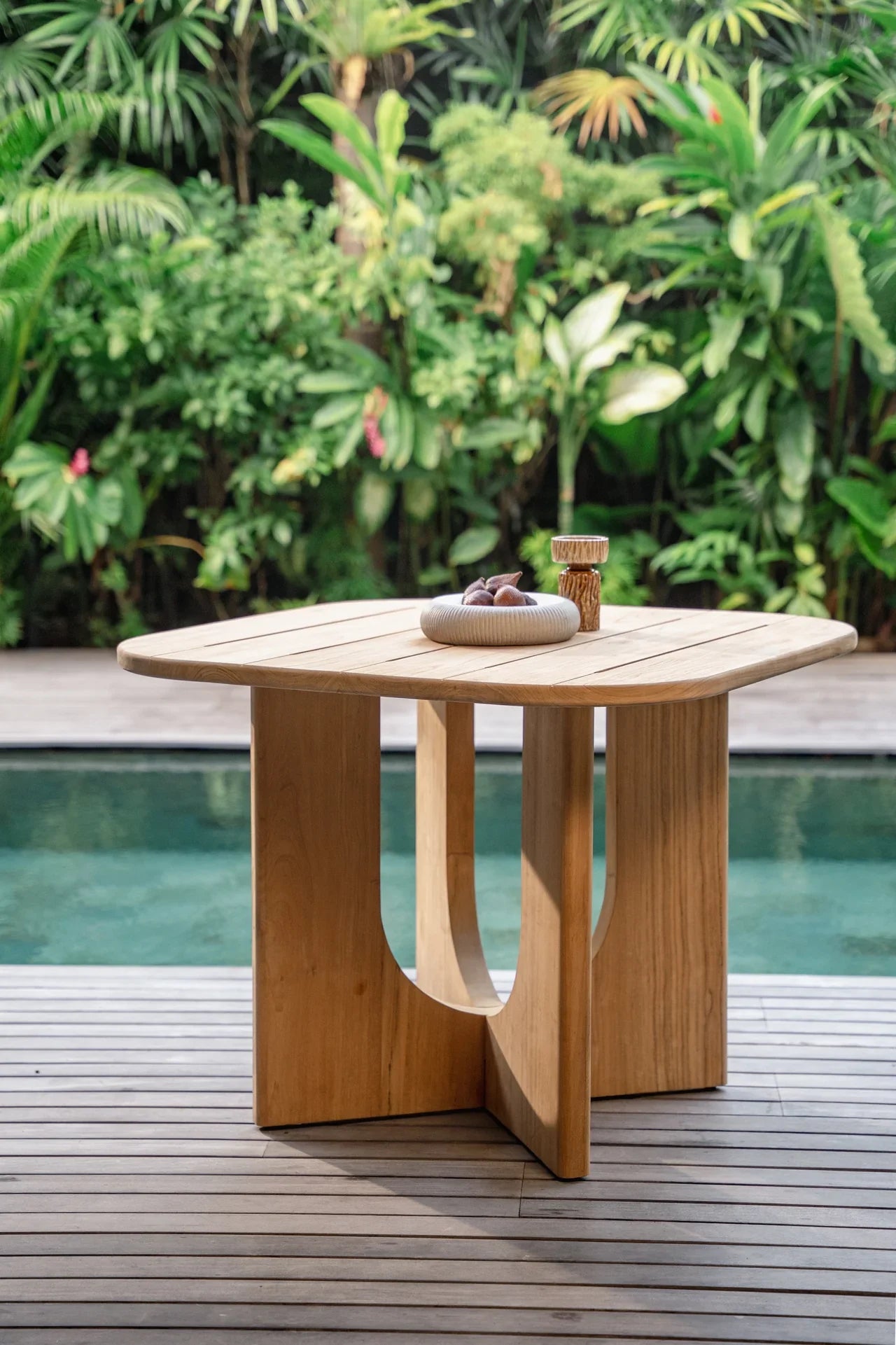 outdoor natural teak dining table by a pool in balinese villa