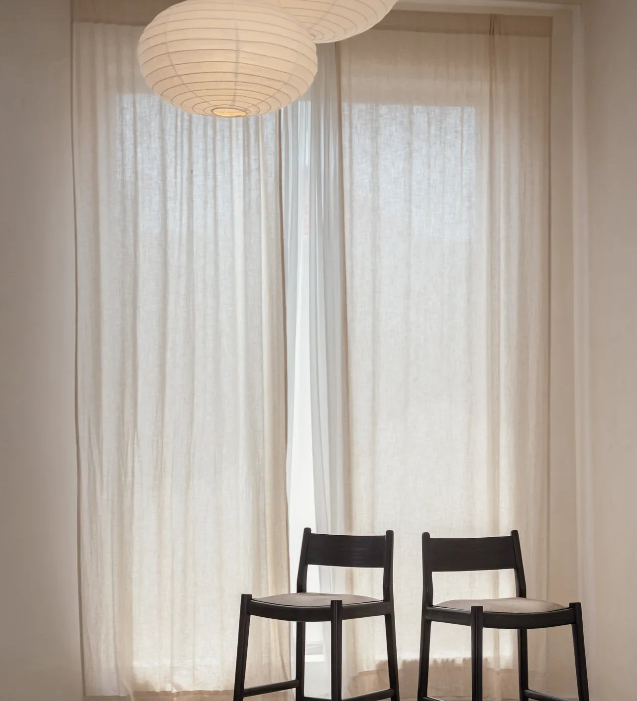 two kitchen counter stools placed next to each other in front of a sheer curtain 