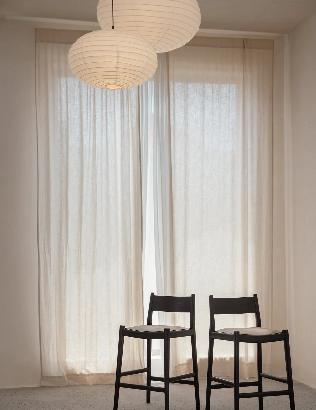 two kitchen counter stools placed next to each other in front of a sheer curtain 