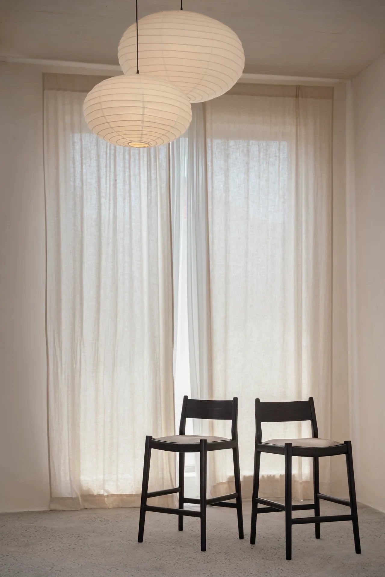 two kitchen counter stools placed next to each other in front of a sheer curtain 
