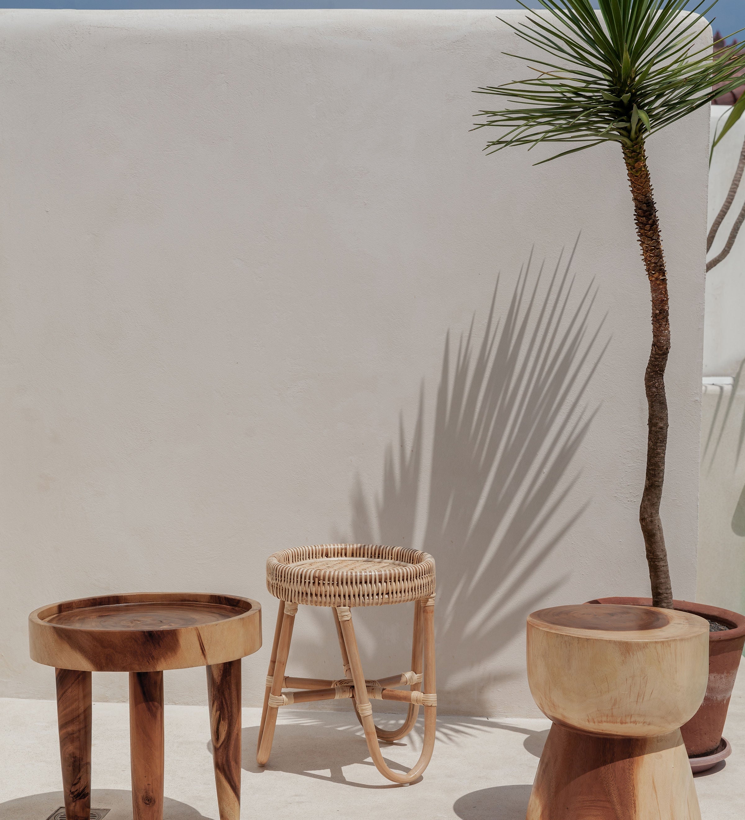 White stone wall with wooden side tables in front