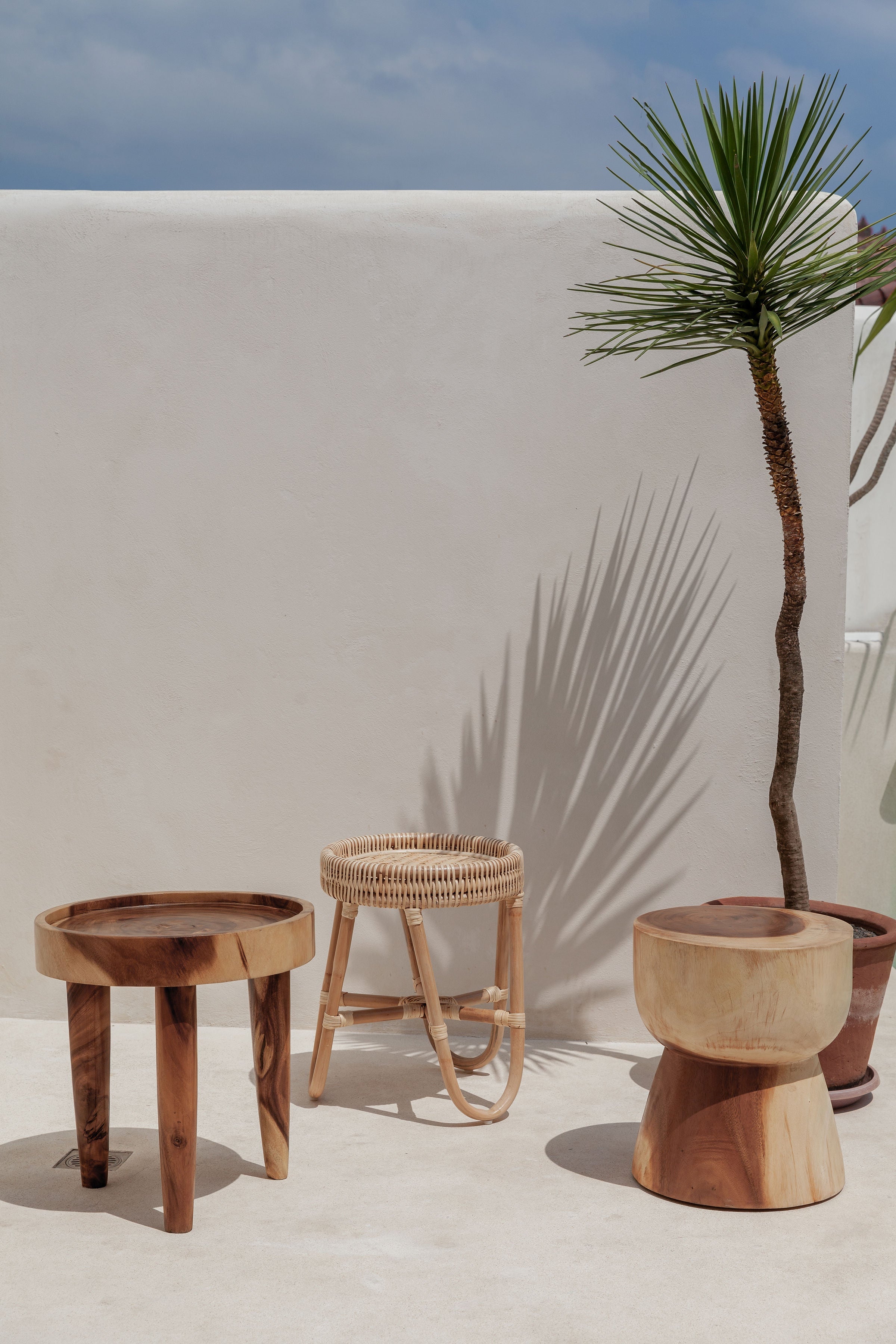 White stone wall with wooden side tables in front