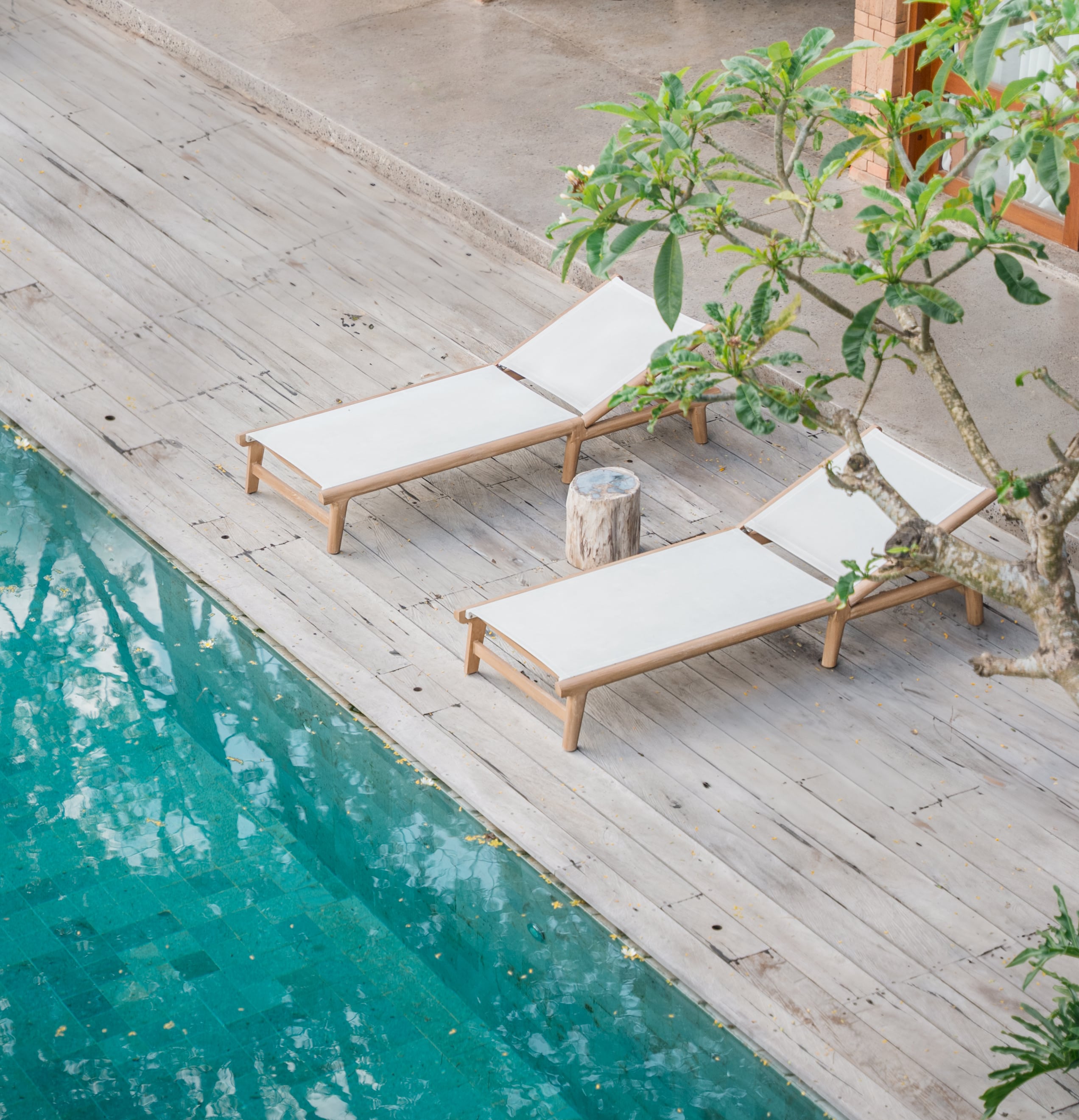 Outdoor pool and deck with two cream and teak lounge chairs