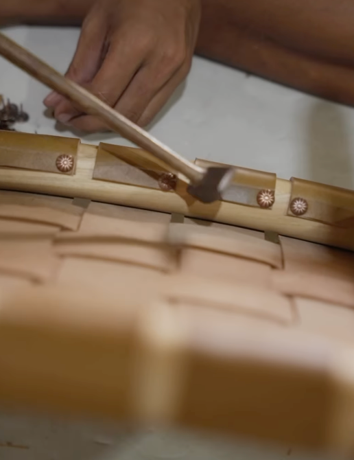 Close up of a man working on a wooden and leather dining stool