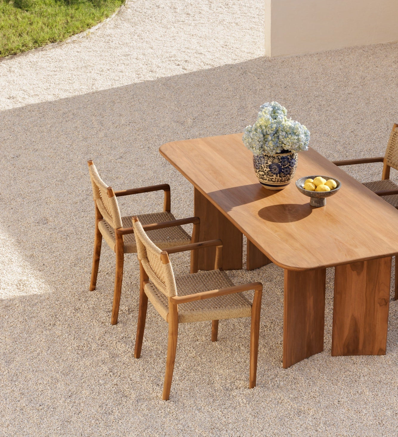 solid teak table and chairs taken from a birds eye view in a neutral colored courtyard