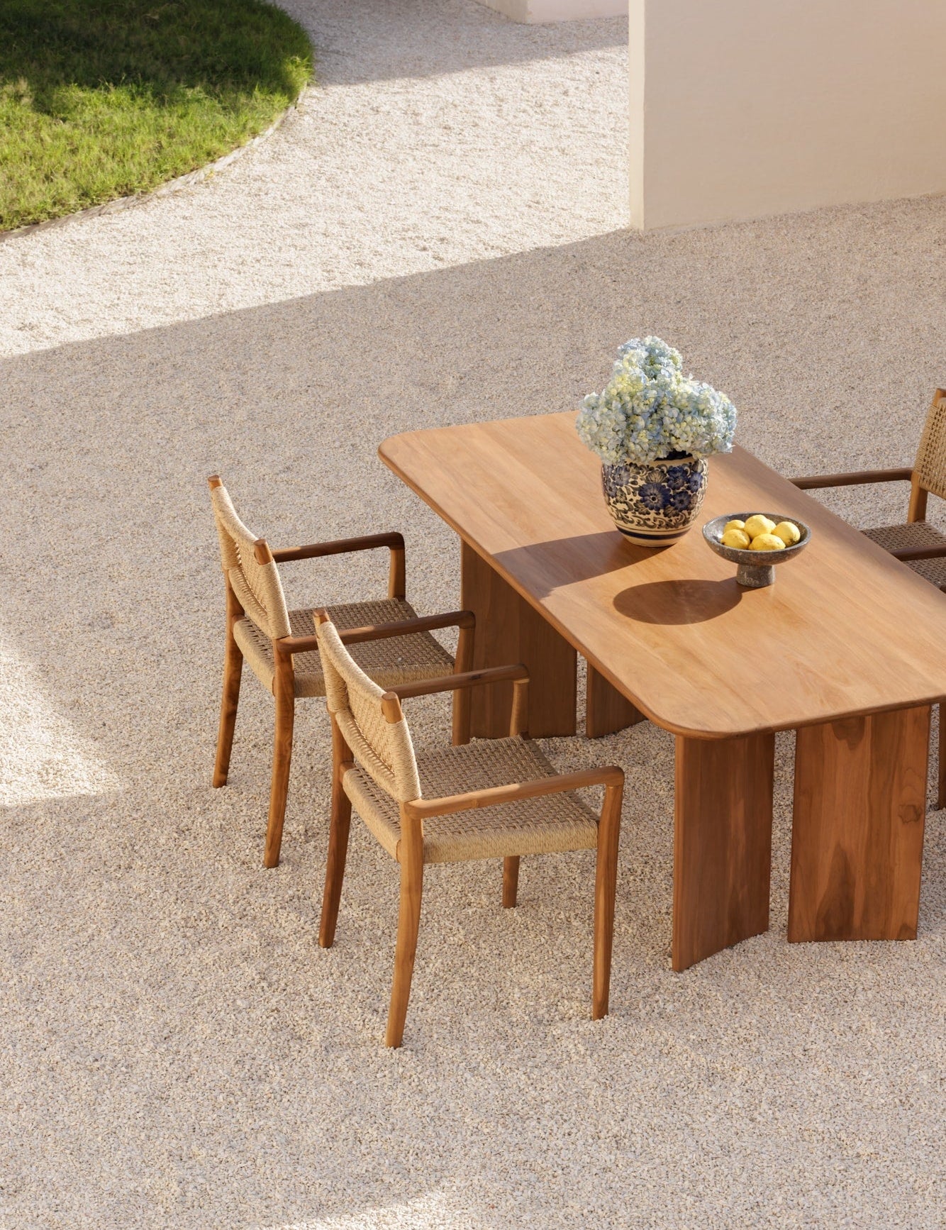 solid teak table and chairs taken from a birds eye view in a neutral colored courtyard