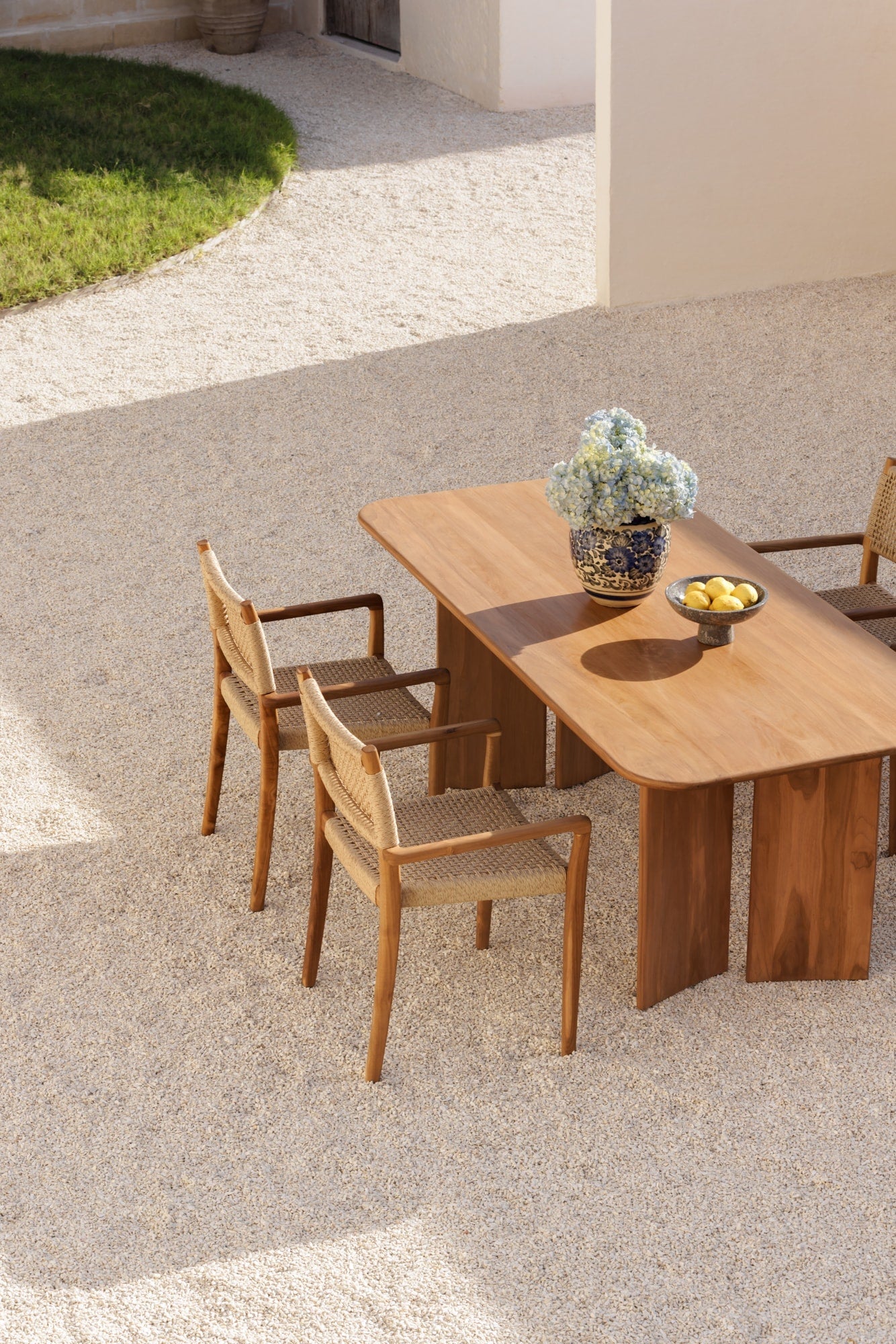 solid teak table and chairs taken from a birds eye view in a neutral colored courtyard