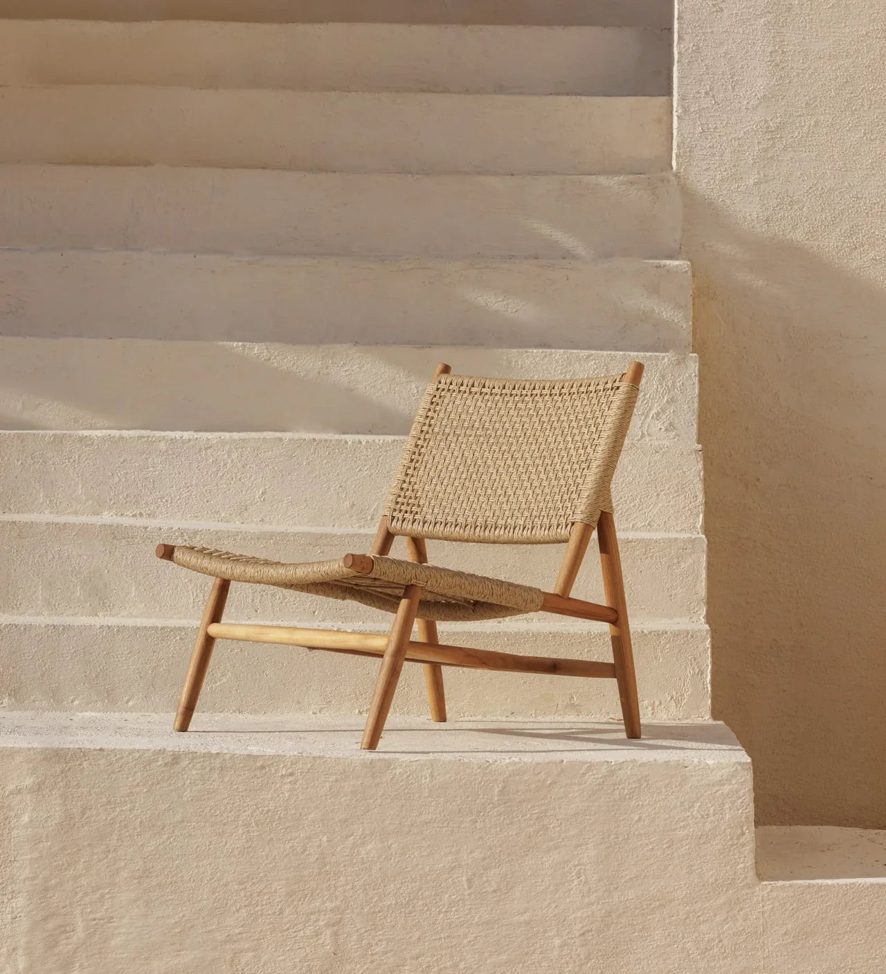 rattan and teak lounge chair on a stone white staircase