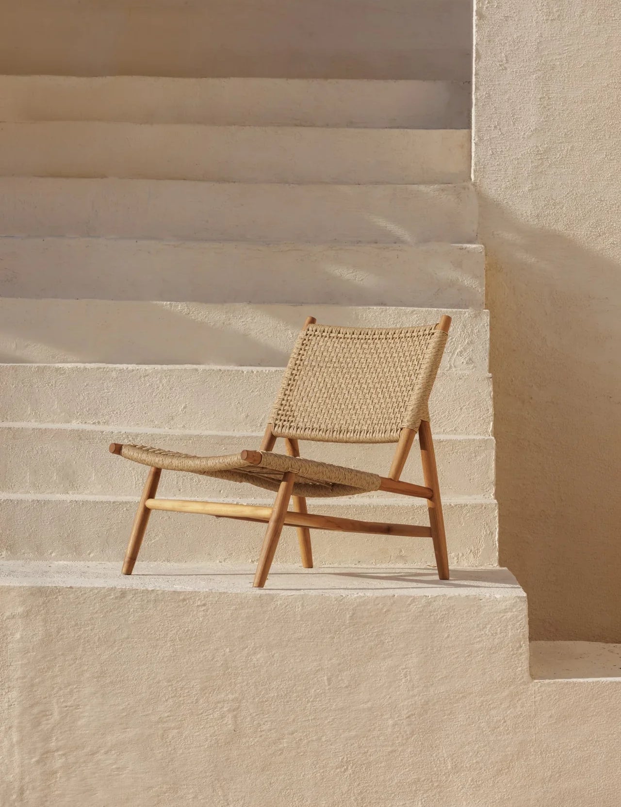 rattan and teak lounge chair on a stone white staircase