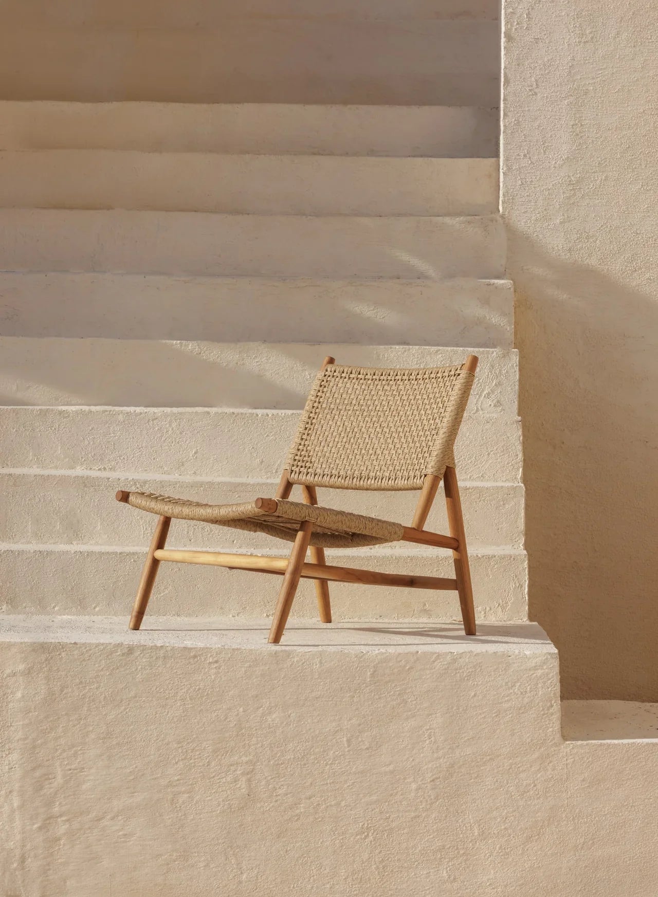 rattan and teak lounge chair on a stone white staircase