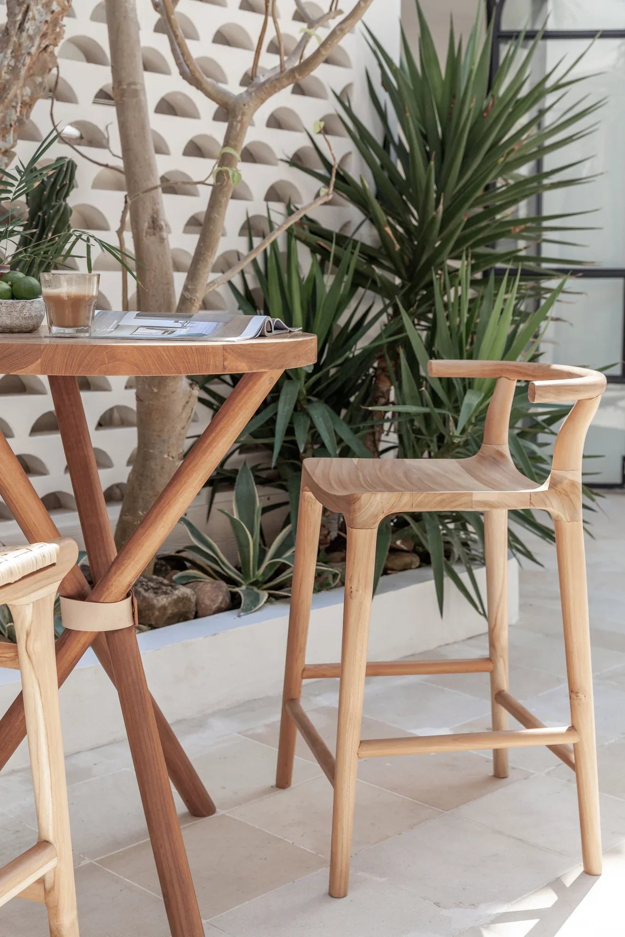 Outdoor setting with two wooden wishbone chairs and a high wooden circular table