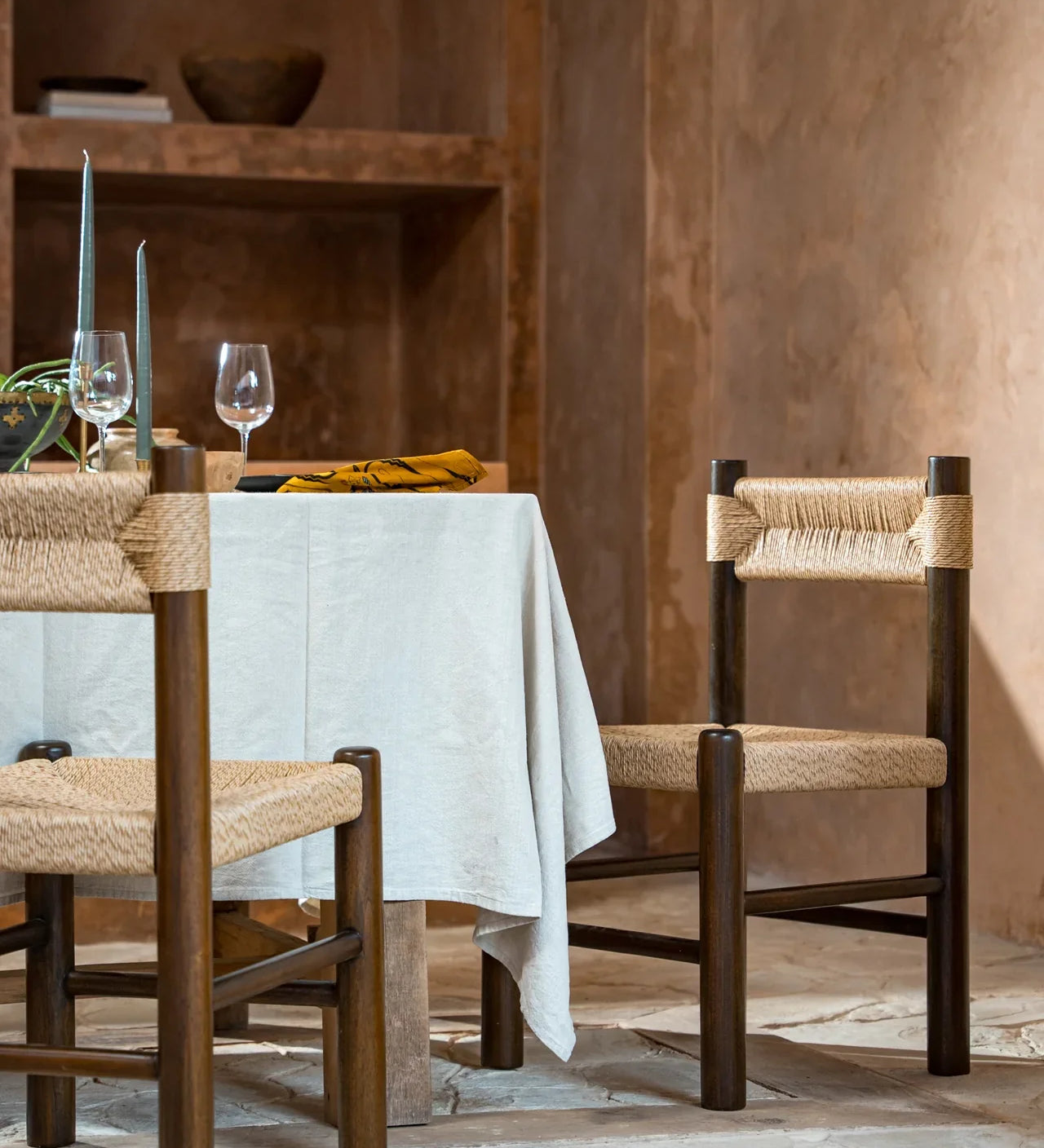 two rattan and teak dining chairs in an alfresco dining setup outdoors 