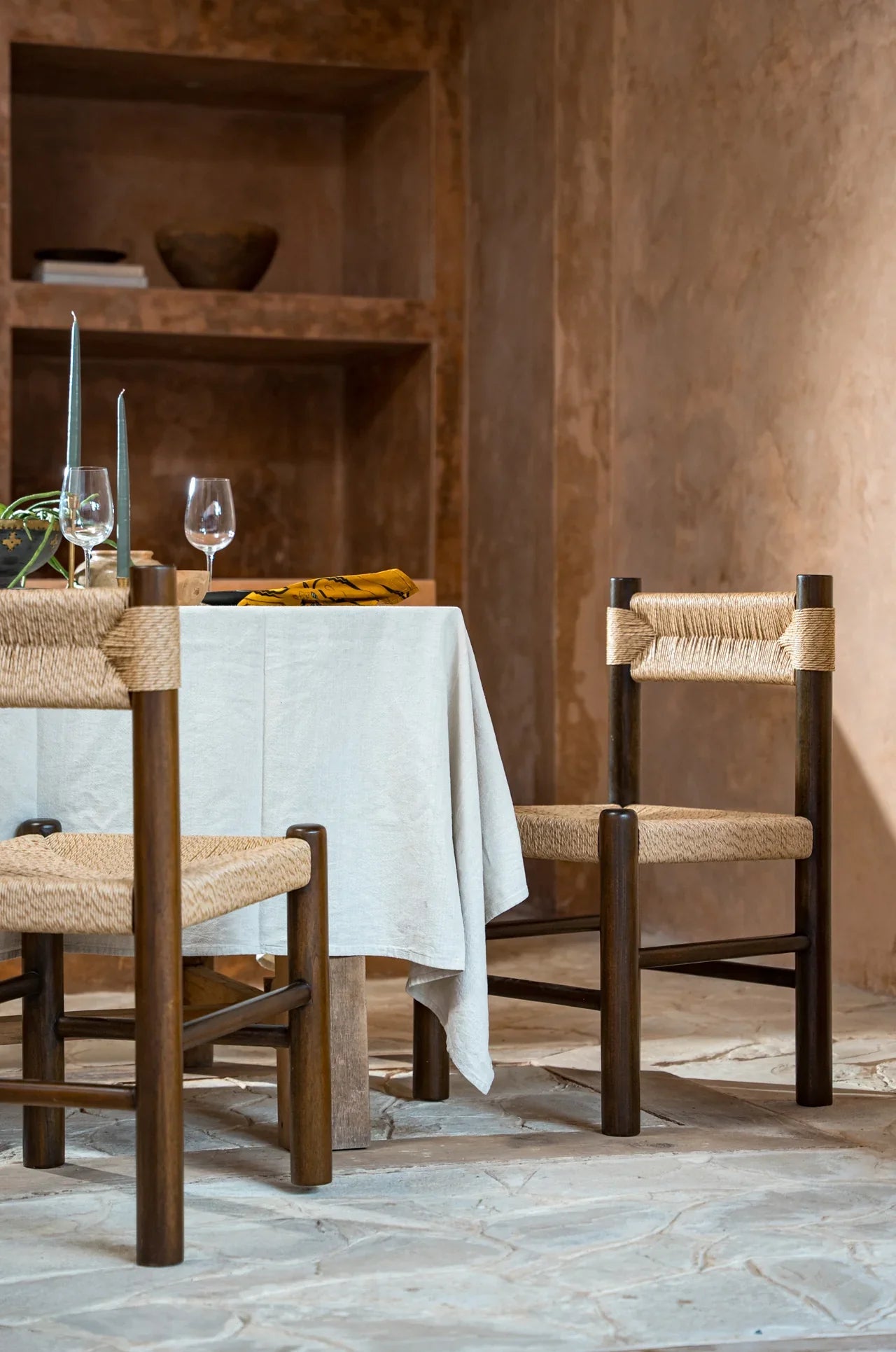 two rattan and teak dining chairs in an alfresco dining setup outdoors 